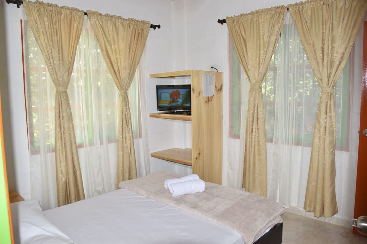 Habitación de Nirvana 1 con cama doble, cortinas y TV